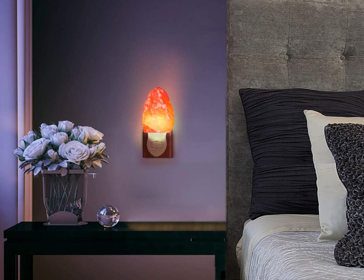 Himalayan salt lamp on a wall next to a bed with pillows