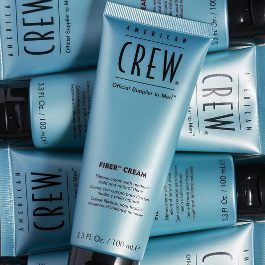 American Crew Fiber Cream tube surrounded by boxes on a dark background