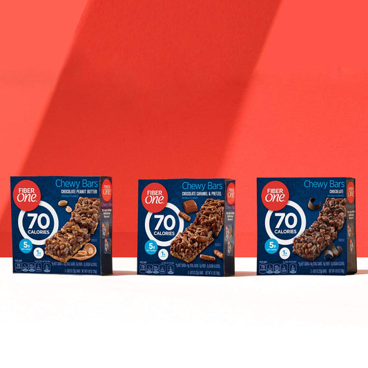 Three boxes of Fiber One Chewy Bars on a white surface with a red background
