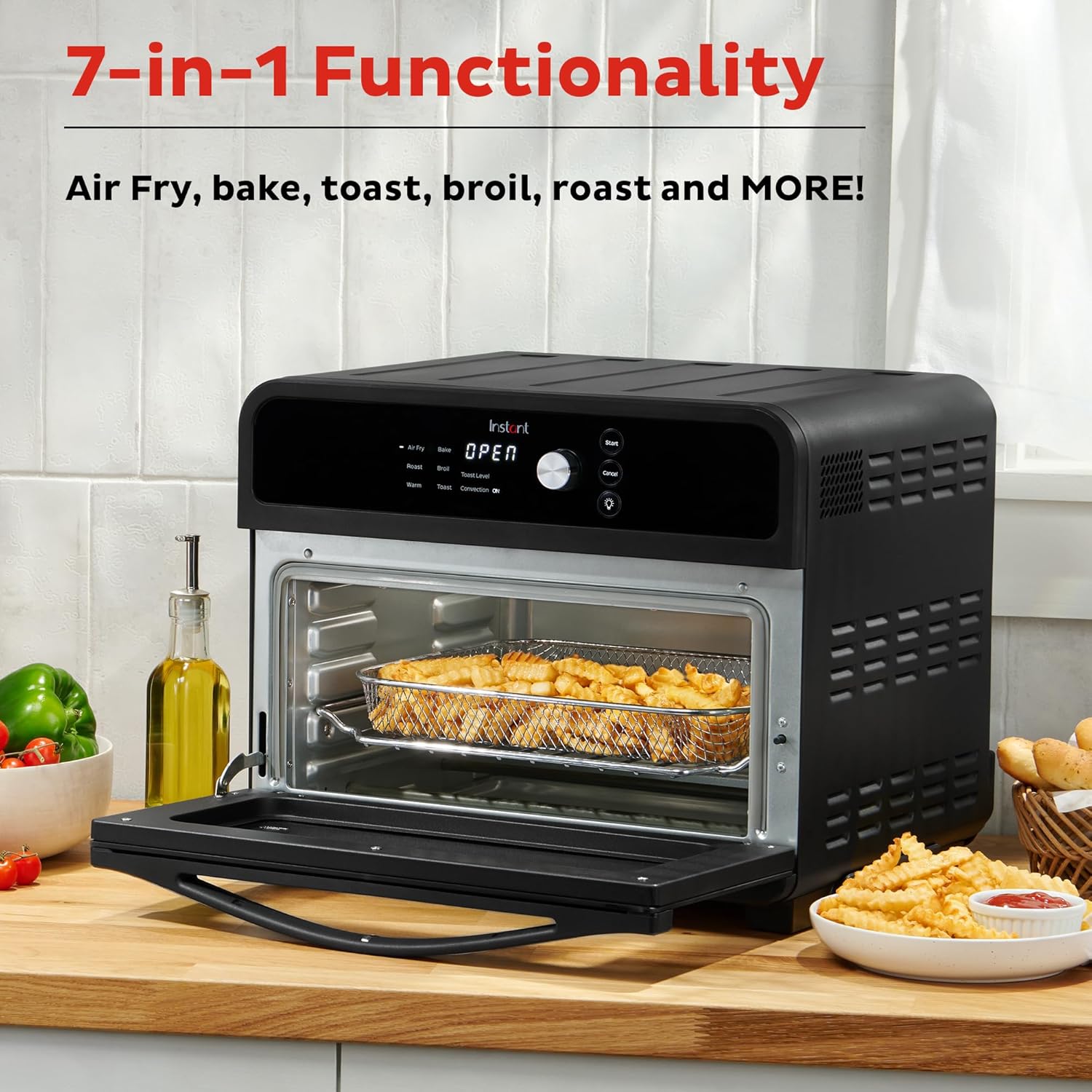 Multifunctional oven with open door showing food inside, surrounded by kitchen items on a wooden countertop.