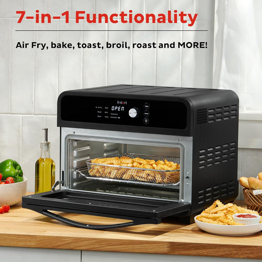 Multifunctional oven with open door showing food inside, surrounded by kitchen items on a wooden countertop.