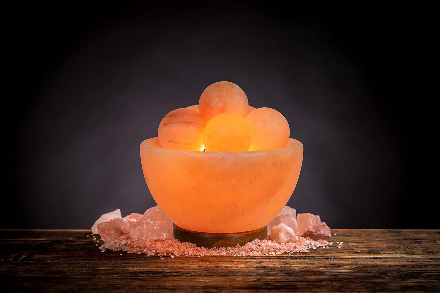 Himalayan salt lamp on a wooden surface with dark background