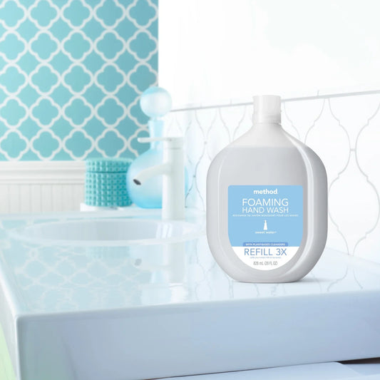 Method foaming hand wash refill bottle on a bathroom counter with a blue tiled wall in the background.