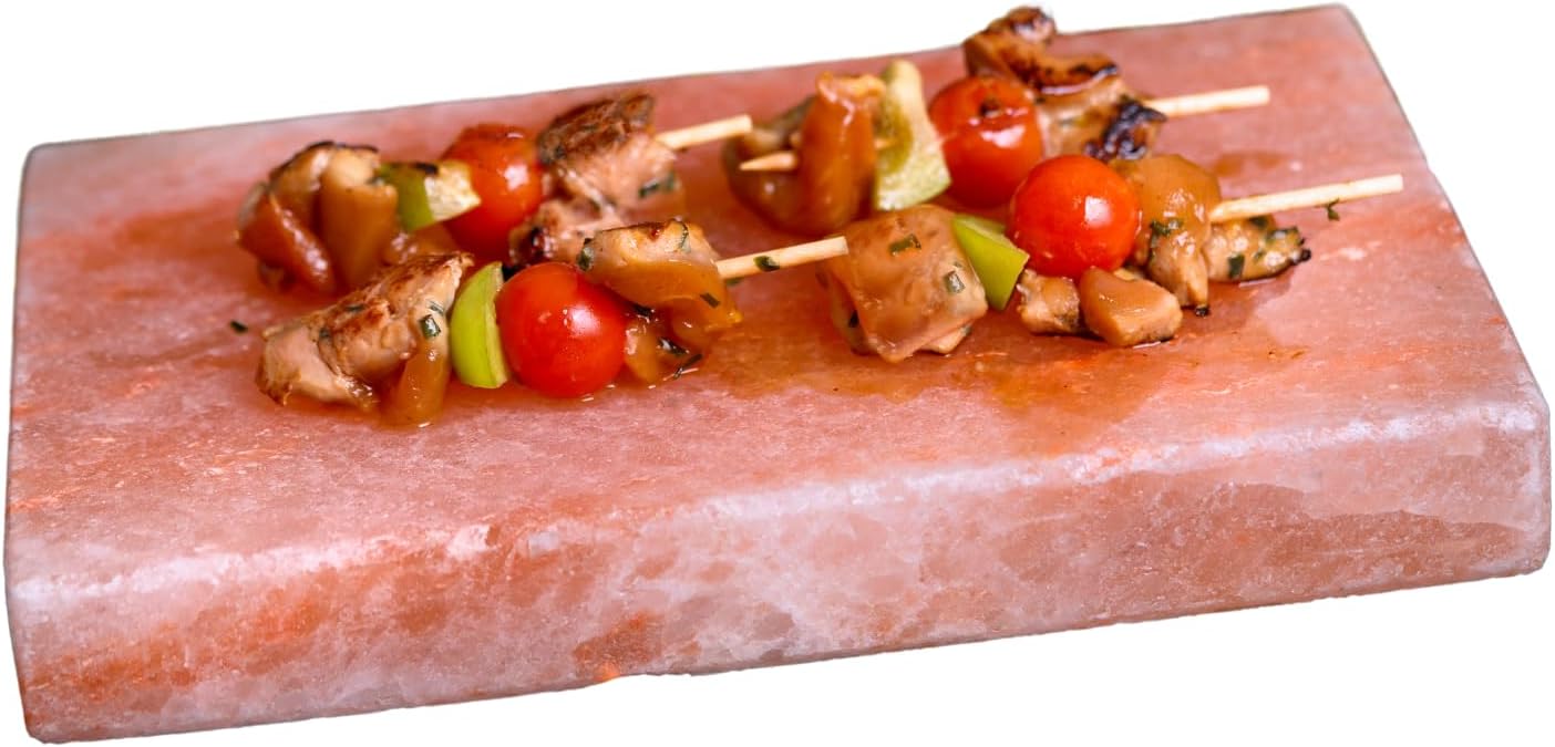 Skewers of grilled chicken and vegetables on a pink Himalayan salt block.