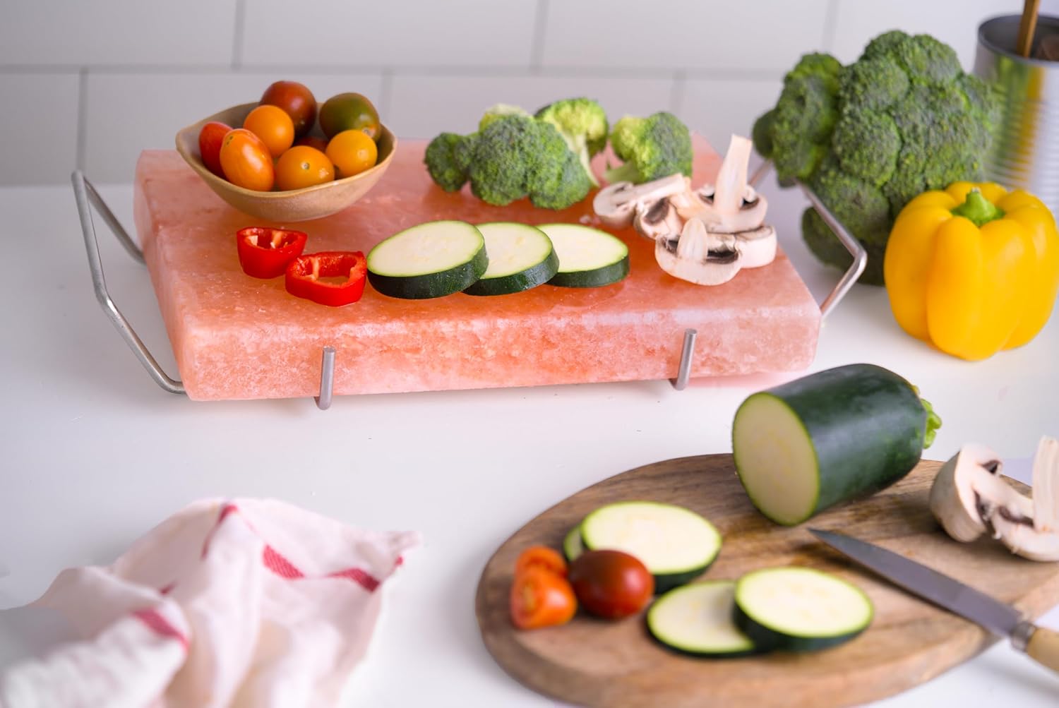 Himalayan salt block with vegetables on a white surface